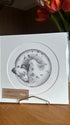 A square white art print or card featuring a circular black-and-white illustration of a dalmatian